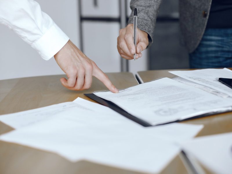 Business men sitting at the lawyers's desk. People signing important documents.